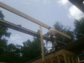 Carpenter setting a ridge beam over a new addition frame — Ice Dam Removal by Roofing Brothers in Humble