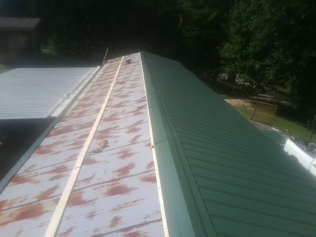Old rusted panels beside newly installed green metal roofing — Wind Damage Roof Repair by Roofing Brothers in Humble