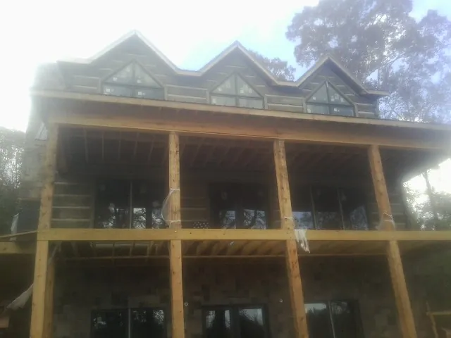 Dormers and porch framing on a large log home under construction — Roof Coating work by our crew in Humble