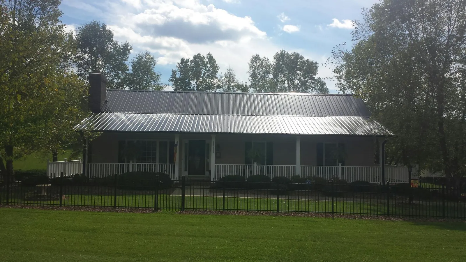 Gray metal roof on a brick ranch with a full width front porch — Gutter Guard Installation work by our crew in Humble